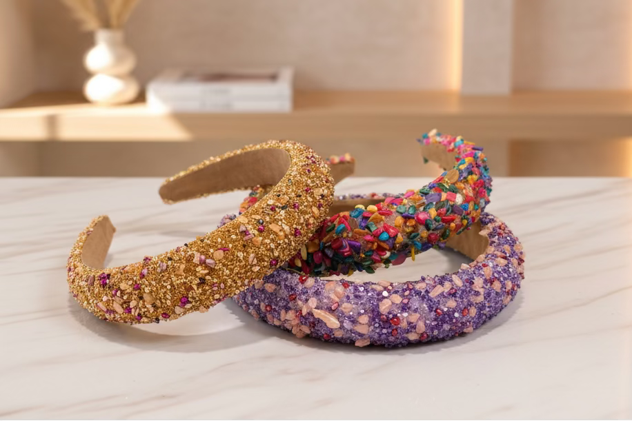 Three handmade headbands covered in decorative sprinkles and glitter, displayed on a dark tabletop.